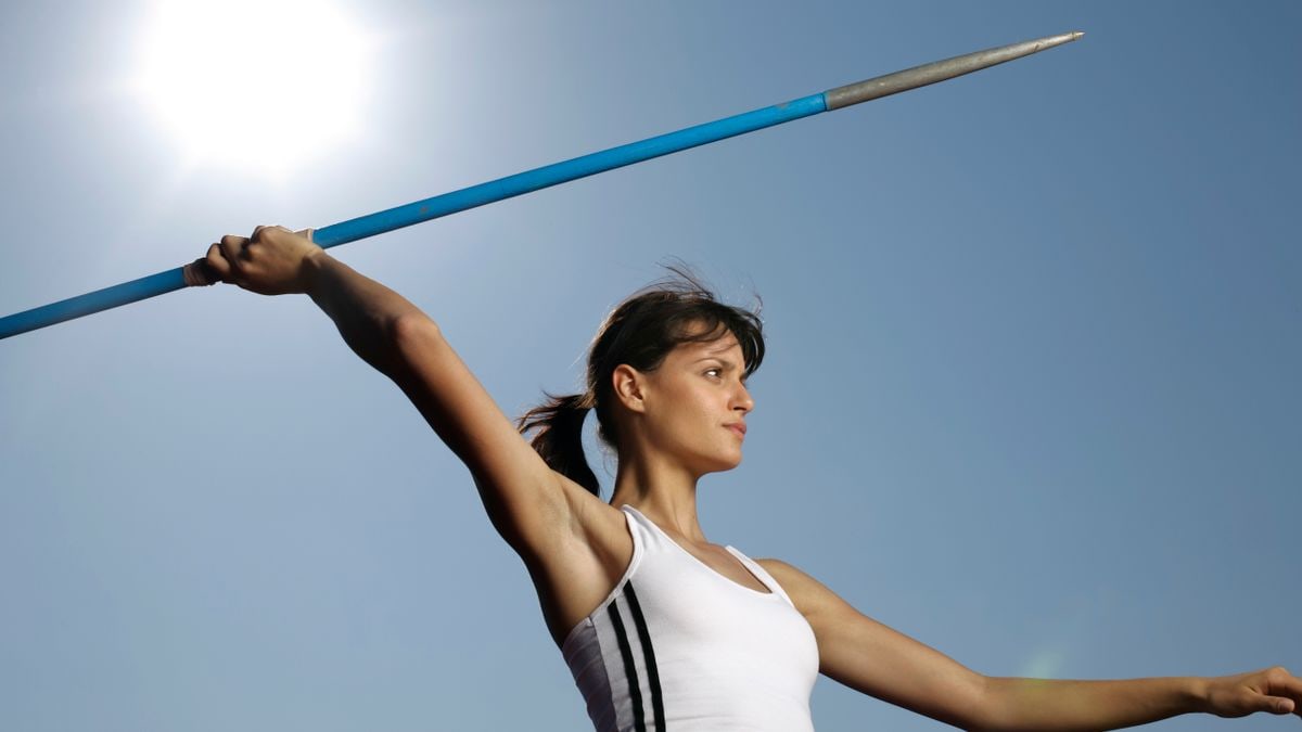 Dynamic shot of a female javelin thrower in action against a bright sky.